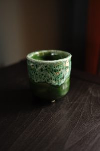 Mini emerald green ceramic planter with cratered glaze and four small feet, measuring 7cm by 7cm