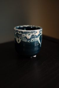 Mini blue ceramic planter with cratered glaze texture and four raised feet, 7cm wide and tall.